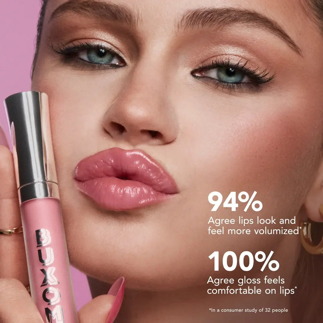 Woman with pink lipstick holding a Buxom lip gloss against a pink background