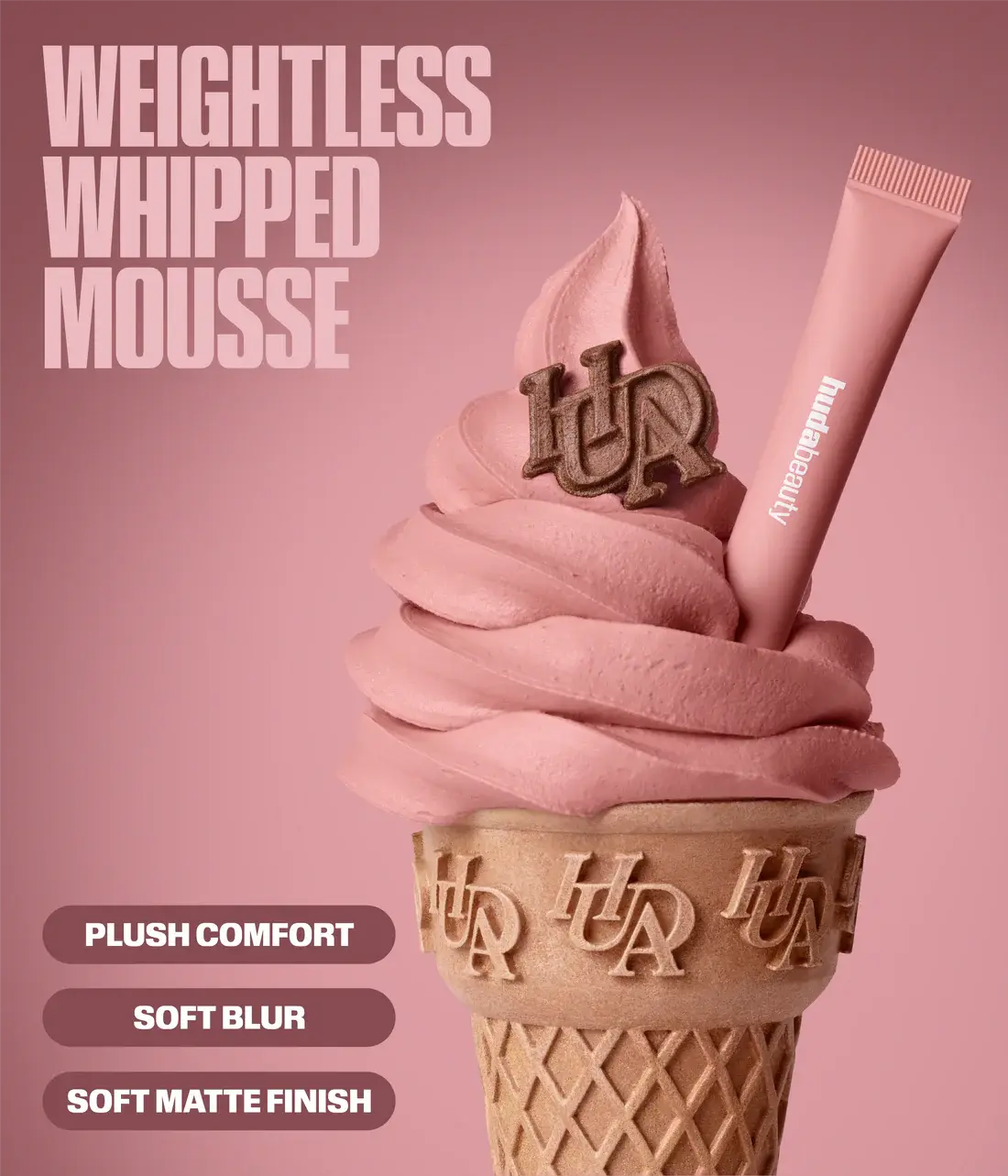 A Huda Beauty Liquid Matte Mousse mockup showing a pink whipped mousse swirl in a waffle cone with a pink tube applicator and a chocolate HAHAHA charm, on a dusty pink background with text reading 'WEIGHTLESS WHIPPED MOUSSE' and product benefits.